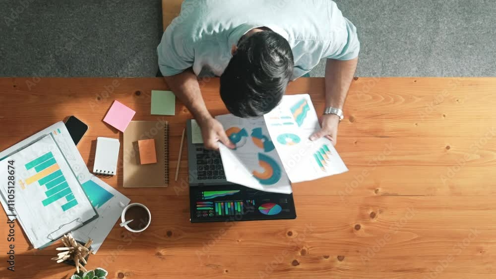 Poster skilled businessman writing idea on colorful sticky notes while looking at data analysis. caucasian 