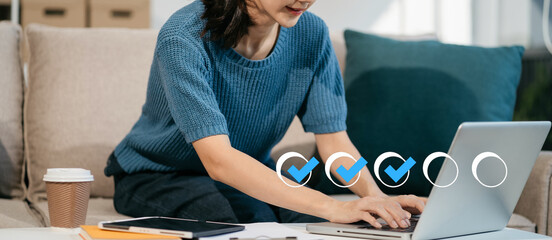 Business performance checklist concept, woman using tablet and laptop doing online checklist...