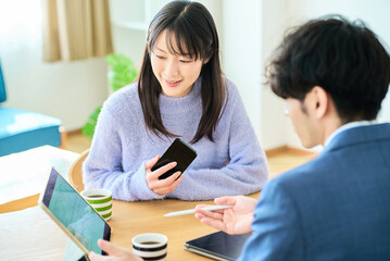 スーツ姿の男性の話を聞く若い女性