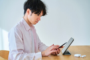 タブレットpcとスマートフォンを見比べる若い男性