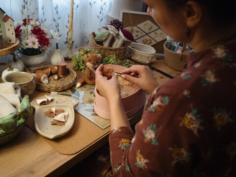 Woman at her cozy desk filling Teddy toy with sawdust