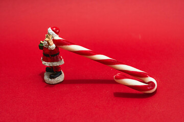 A figure of Santa Claus pulling a candy cane on a red background.