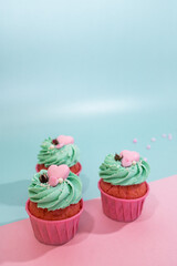 Cupcakes on a pink and mint color background. Pink cupcake with mint cream and pink heart