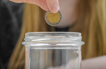 Wrzucać monetę 5 złotych polskich do słoika skarbonki  © Paweł Kacperek