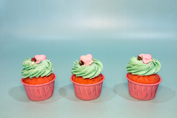Cupcakes with sprinkles. Cupcake on a mint color background. Pink cupcake with mint cream and pink heart
