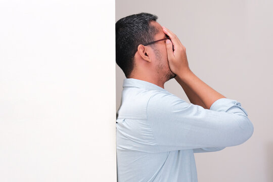 A man leaning on the wall showing sad expression with hand covering his face