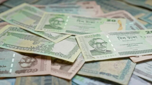 Bangladeshi banknotes scattered on a surface showcasing various denominations and featuring prominent figures, highlighting the currency of bangladesh.