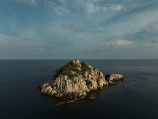 Aerial image of Isolated rock island on the middle of the ocean at golden hour