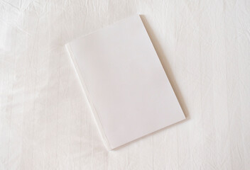 White magazine mockup on white hotel bed