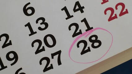 The 28 number in the calendar is marked with a marker as an important date. Close-up.