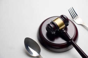 Judges gavel with fork and spoon on a white background with copy space, close-up. Sanitary inspection, food law and justice concept