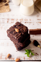Chocolate brownies with melted chocolate topping, almond and leaves mint with glass of milk on...