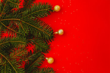 red christmas background. Minimalist Christmas arrangement with fresh evergreen branches and golden pinecones on a vibrant red background, perfect for holiday designs.