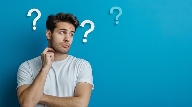 A thinking man looking at question marks on a blue wall
