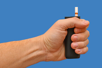 A device for electrically heating tobacco with a stick is held in the hand against a blue...