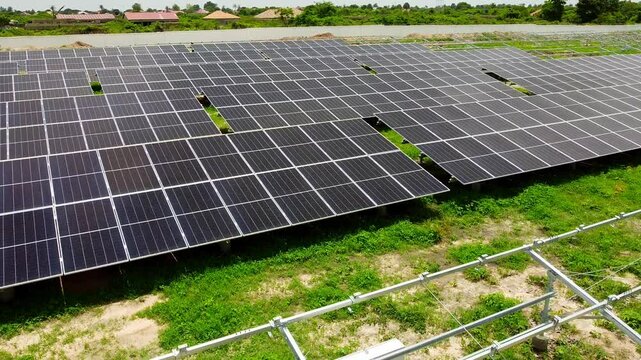 Aerial low closeup sliding view over solar panel arrays with visible combiner box at solar PV power plant