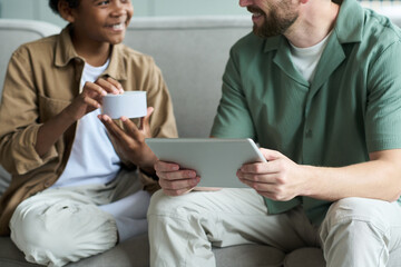 Smiling diverse individuals interacting with a tablet and smart speaker, engrossed in a lively...