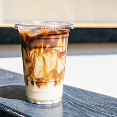 Iced caramel macchiato in a plastic cup, showing the beautiful swirls of coffee, milk, and caramel isolated