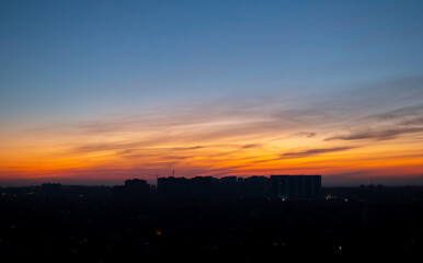 Silhouettes of urban buildings during sunset with dramatic clouds. Evening cityscape photography