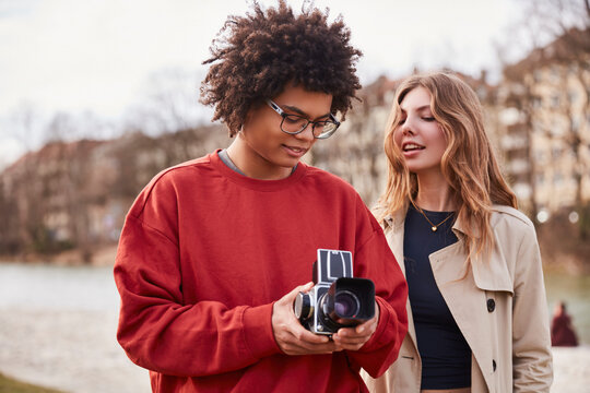 Young mixed race couple taking pictures with a vintage analog camera. Munich, Germany