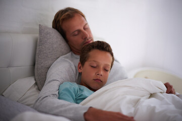 Fototapeta premium Father, sleeping and hug kid in home, love and support child in dream or nap for comfort. Daddy, boy and embrace son for peace or security in rest, care and family fatigue for bonding in bedroom
