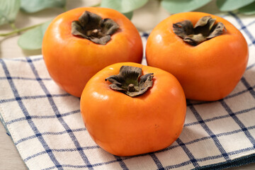 Fresh ripe persimmon fruit on wooden table background.