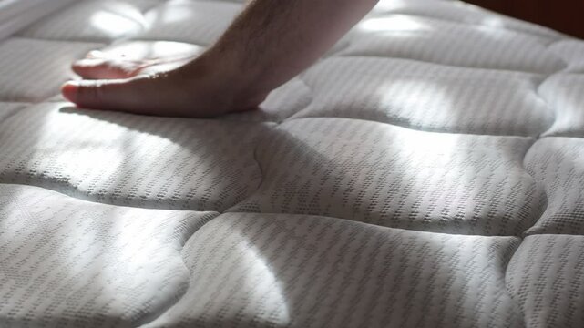 a man strokes a new orthopedic mattress with his hand, assessing the quality before buying in a store, 4k video
