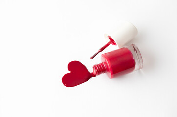 Red nail polish swatch in heart shape and nail bottle with brush on white background, love, manicure concept