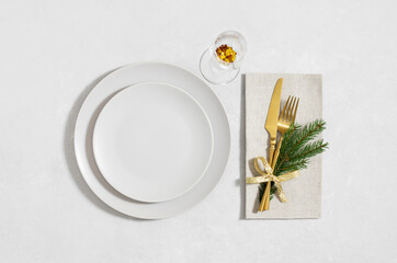 Beige empty plate with golden cutlery and a glass on white background. Christmas table setting....