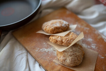 Homemade chicken cutlets arranged on a wooden board with parchment paper, styled in a rustic kitchen setting. Warm natural light and cozy details make it perfect for food photography or healthy meal c