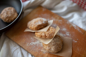 Homemade vegan patties placed on a rustic wooden board with parchment paper, styled in a cozy kitchen setting. Warm natural light highlights the texture, ideal for food photography or plant-based meal