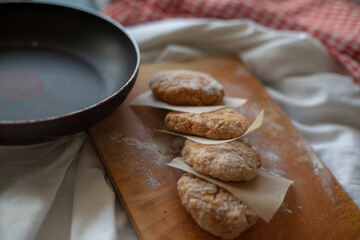 Homemade chicken cutlets arranged on a wooden board with parchment paper, styled in a rustic kitchen setting. Warm natural light and cozy details make it perfect for food photography or healthy meal c