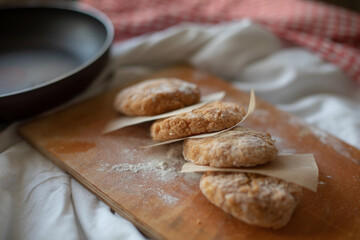 Homemade chicken cutlets arranged on a wooden board with parchment paper, styled in a rustic kitchen setting. Warm natural light and cozy details make it perfect for food photography or healthy meal c