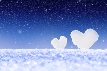 Winter background with two snow hearts in the snow with copy space.