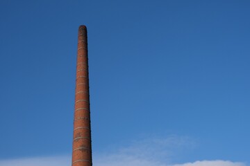 Fototapeta premium Industrial Brick Chimney Against Blue Sky in Wroclaw