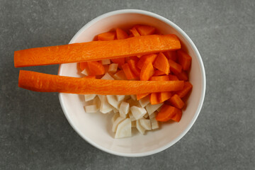 Finely chopped parsley root and carrot in a white bowl.