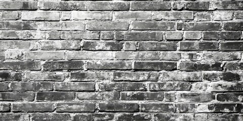 Fototapeta premium Desaturated brick wall background featuring clean black and white brickwork. This brick wall texture offers a grunge vintage aesthetic with ample copy space for creative purposes.