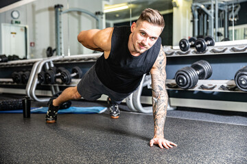 Junger Mann in Sportkleidung trainiert mit Sportgeräten im Fitnessstudio konzentriert und motiviert