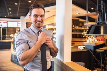 Junger Business Mann im Café arbeitet mit Laptop und Telefon produktiv in einem modernen Arbeitsumfeld