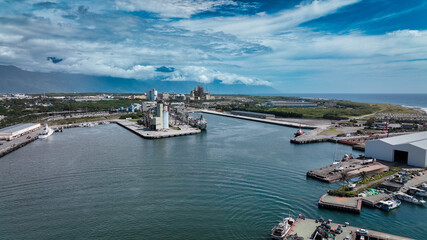 Obraz premium Aerial view of Hualien harbor showcasing boats and coastal landscape under blue sky