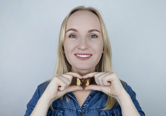 Prevention of thyroid disease. Woman holding a brazil nut in the shape of a thyroid gland. Nut rich...