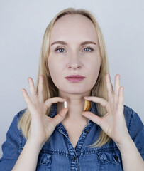 Woman considers what is better to eat to replenish selenium - a dietary supplement or a Brazil nut....