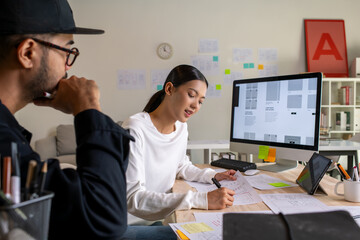 UX UI designers discussing and brainstorming on wireframes for a website and mobile app prototype,...