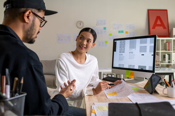 UX UI designers discussing and brainstorming on wireframes for a website and mobile app prototype,...