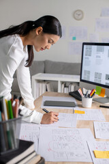 UX UI designer working on wireframes for a website and mobile app prototype, surrounded by sketches...