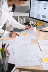 UX UI designer working on wireframes for a website and mobile app prototype, surrounded by sketches...