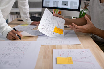 UX UI designers discussing and brainstorming on wireframes for a website and mobile app prototype,...