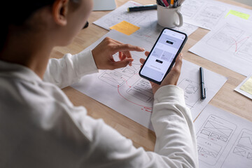 UX UI designer testing prototype on a phone, discussing and brainstorming on wireframes for a...