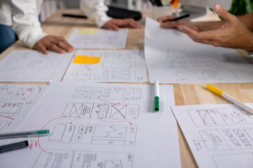 UX UI designers discussing and brainstorming on wireframes for a website and mobile app prototype,...