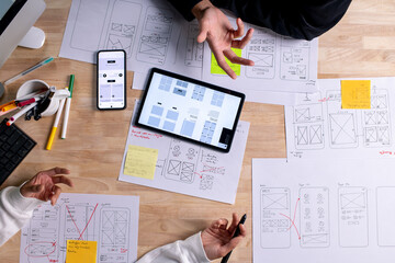 UX UI designers discussing and brainstorming on wireframes for a website and mobile app prototype,...